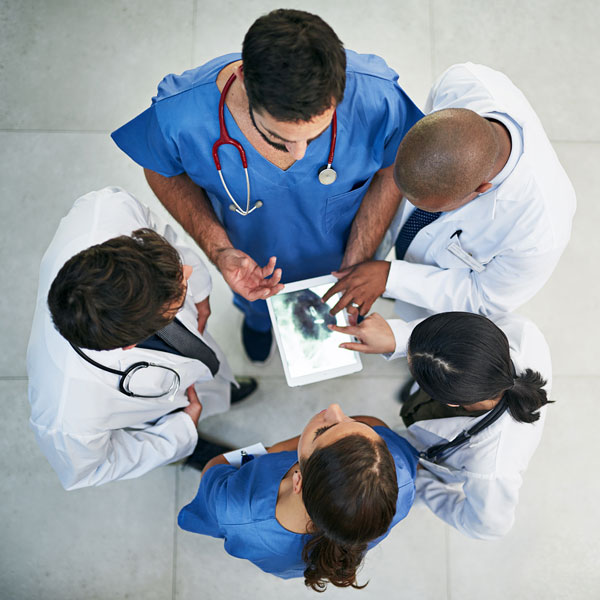 Top down view of group of physicians discussing an X-ray on a mobile device.