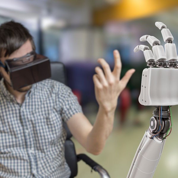Man in wheelchair wearing virtual reality goggles uses his hand to control a robotic hand.